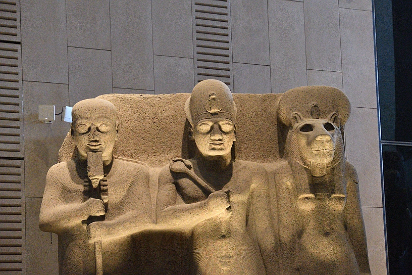 23 MAK_7060.jpg - Gruppo in granito rosa, conosciuto come la triade di Menfi: il dio Ptah, al centro il faraone Ramses II e la dea Sekmet, simbolo di forza e protezione. Con questa scultura Ramses II si proclama collegamento vivente tra il cielo e la terra.